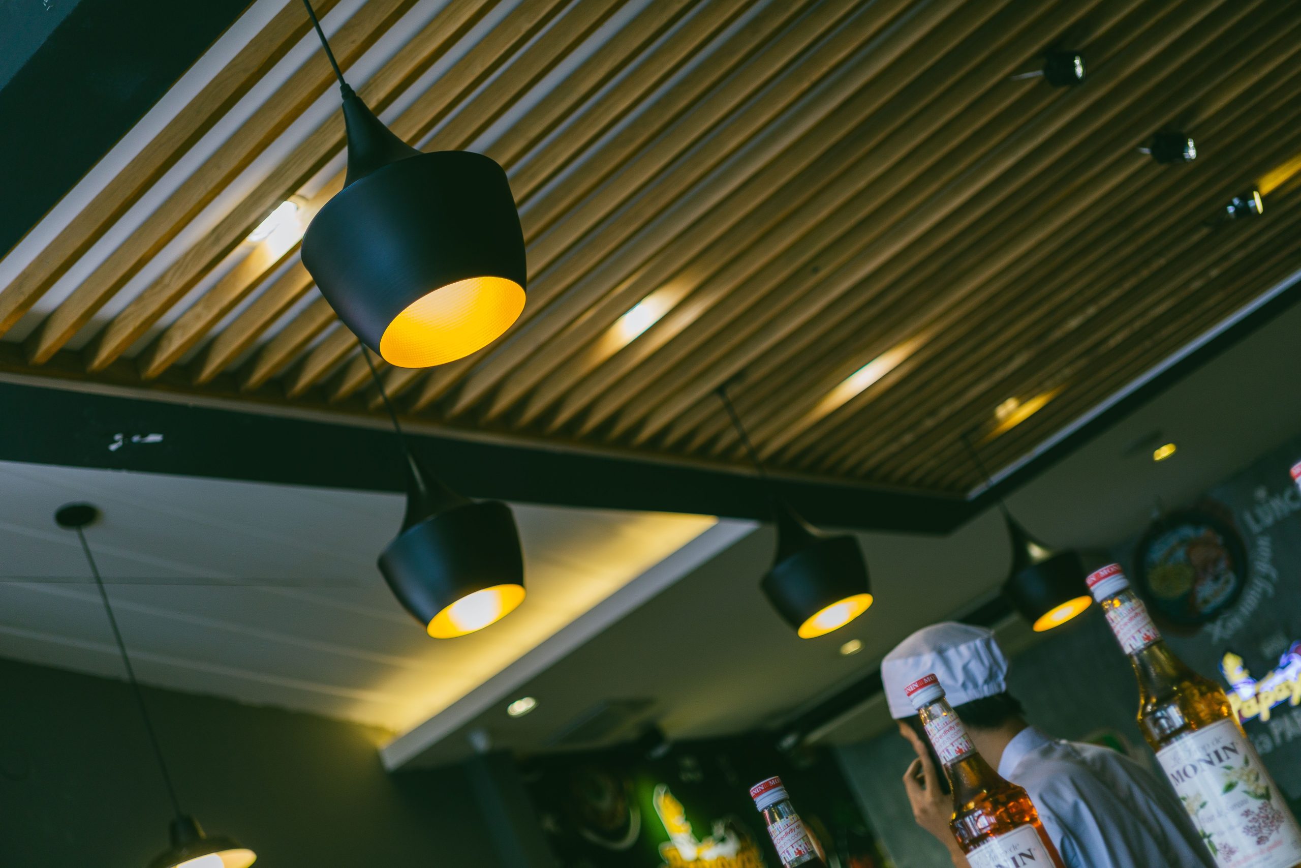 Restaurant moderne avec lampes design et bouteilles.