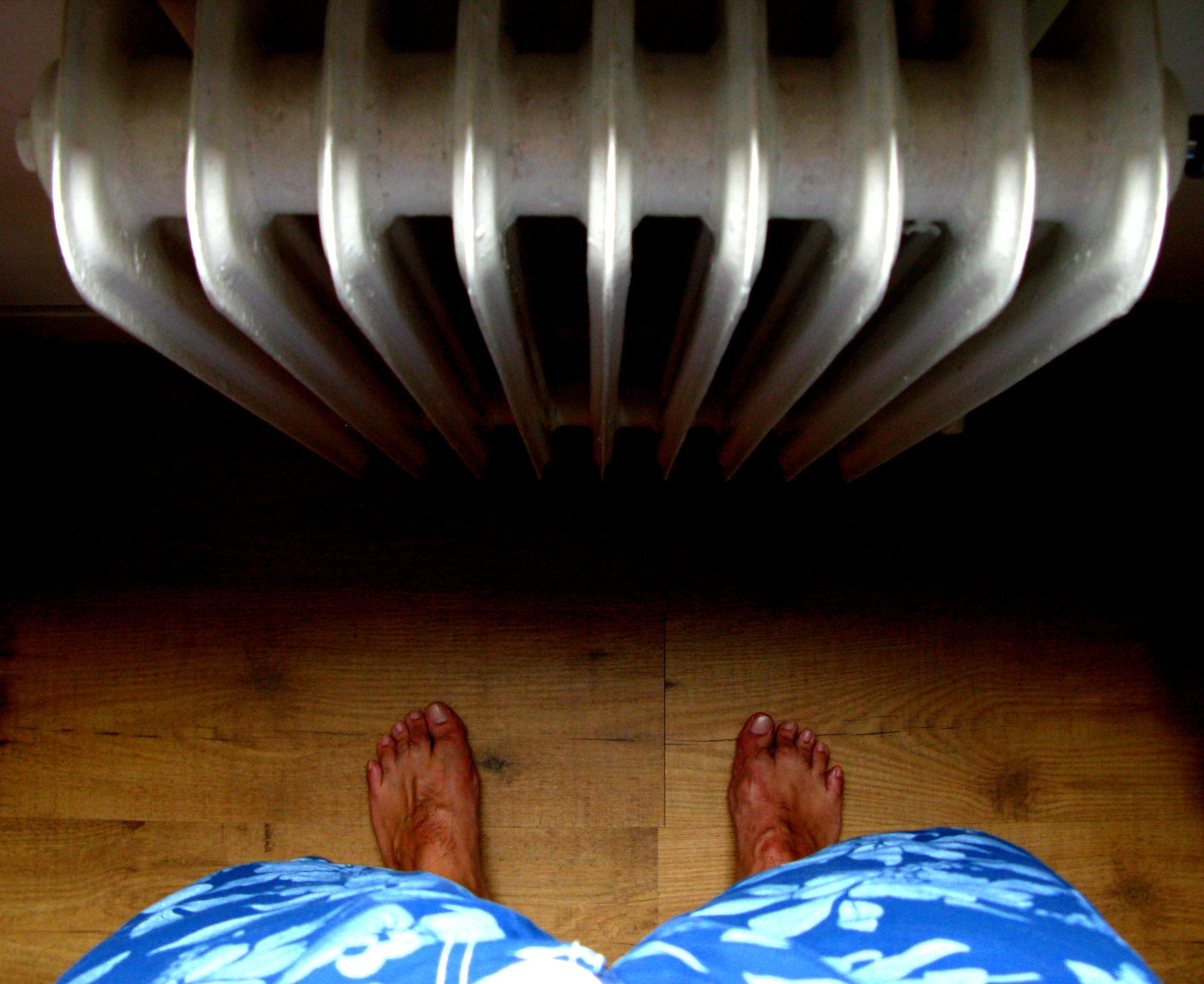 Pieds nus près radiateur sur parquet bois