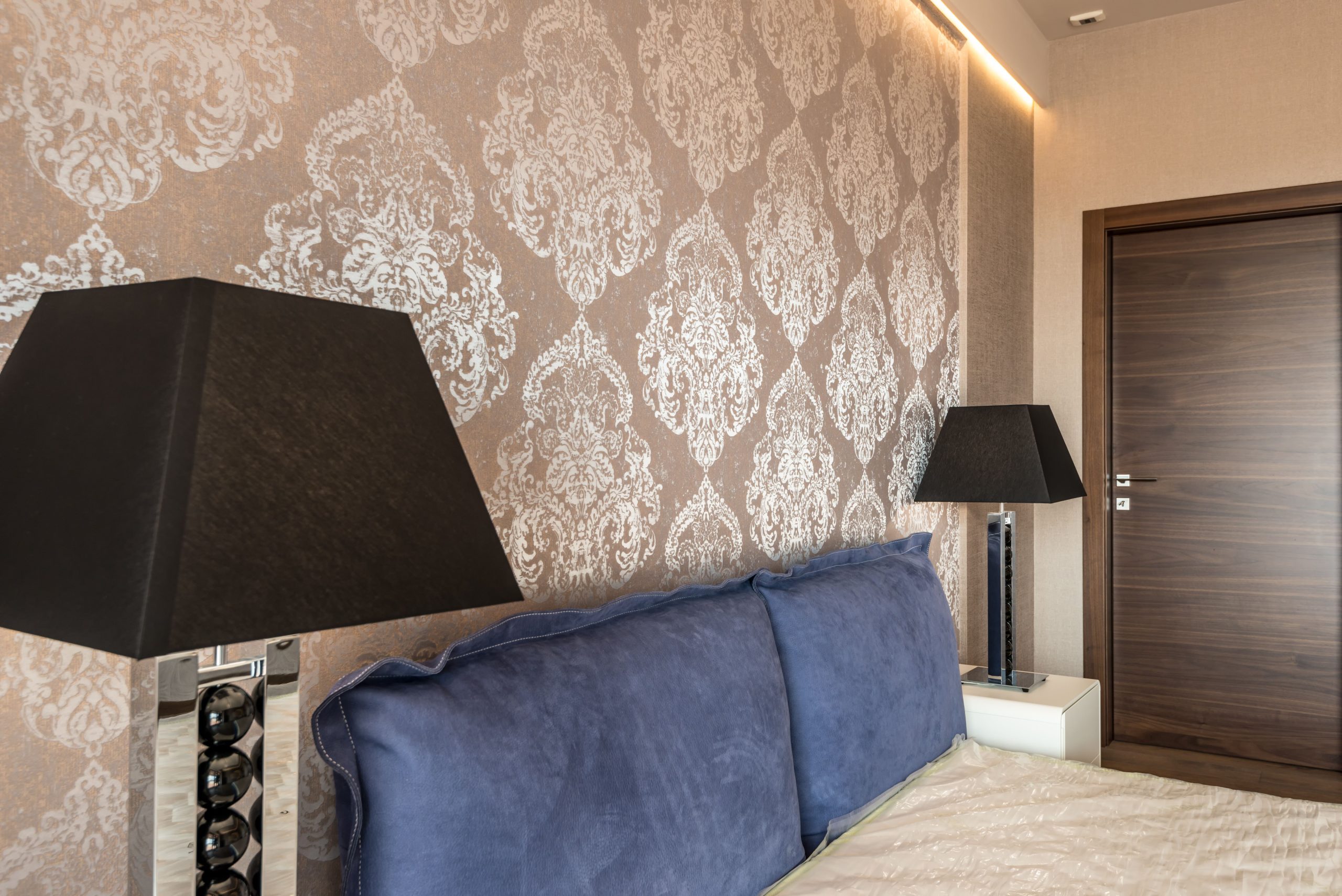 Chambre moderne avec papier peint élégant et lampes noires.