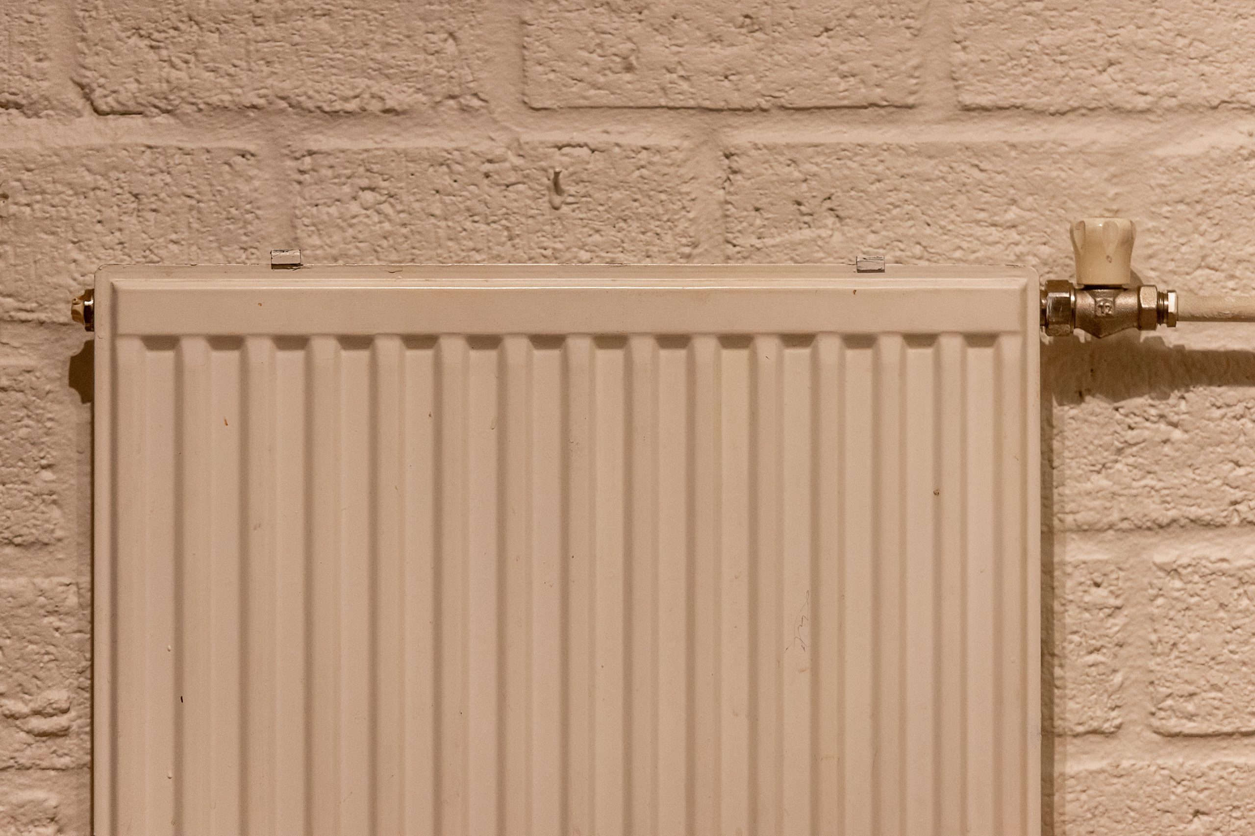 Radiateur blanc monté sur mur brique texturé